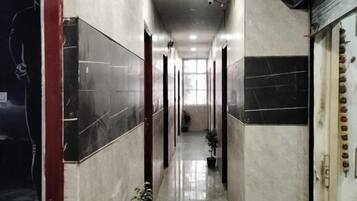 Un largo y estrecho pasillo con paredes de azulejos y piso pulido, que conduce a una puerta al final.