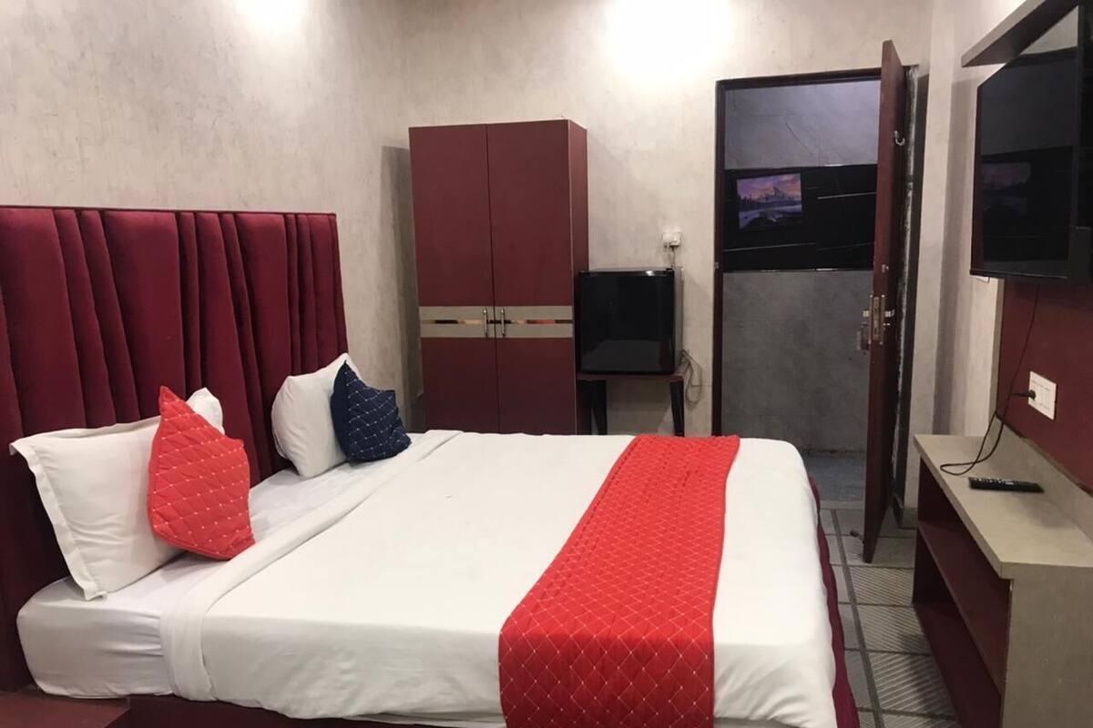 A hotel room with a bed, a wardrobe, a television, and a door.