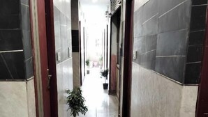 Egy folyosó, melynek a falai csempével vannak burkolva, és egy virágtartóban lévő növény áll benne.