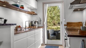 Eine moderne Küche mit weißen Schränken, Holzböden und Blick ins Freie.
