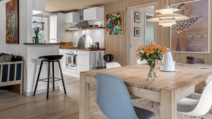Eine moderne Küche mit weißen Schränken, einer Holzbalkendecke und einem Essbereich mit einem Holztisch und Stühlen.
