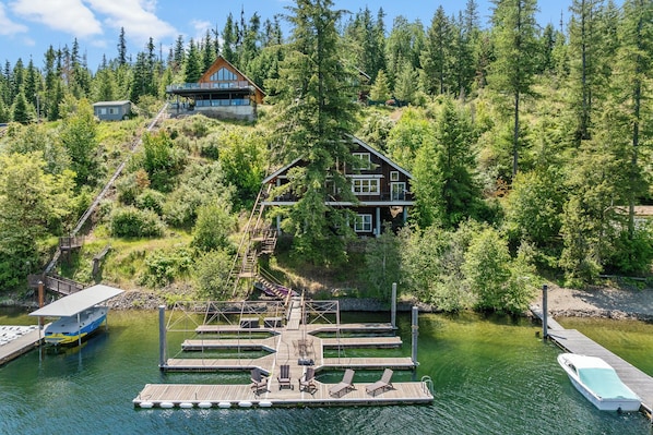 A cabin with a deck and dock, surrounded by forest. - New Listing! Lakefront | Spacious Deck | Private Dock | Hot Tub | Tram (Harrison)