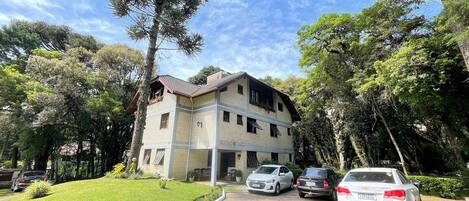 Un edificio de dos pisos con fachada de ladrillo, techo de tejas y camino de entrada pavimentado.