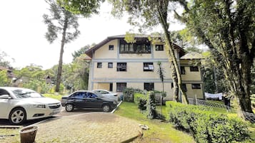 Um edifício de dois andares com fachada de tijolos, uma entrada pavimentada e um carro estacionado em frente.