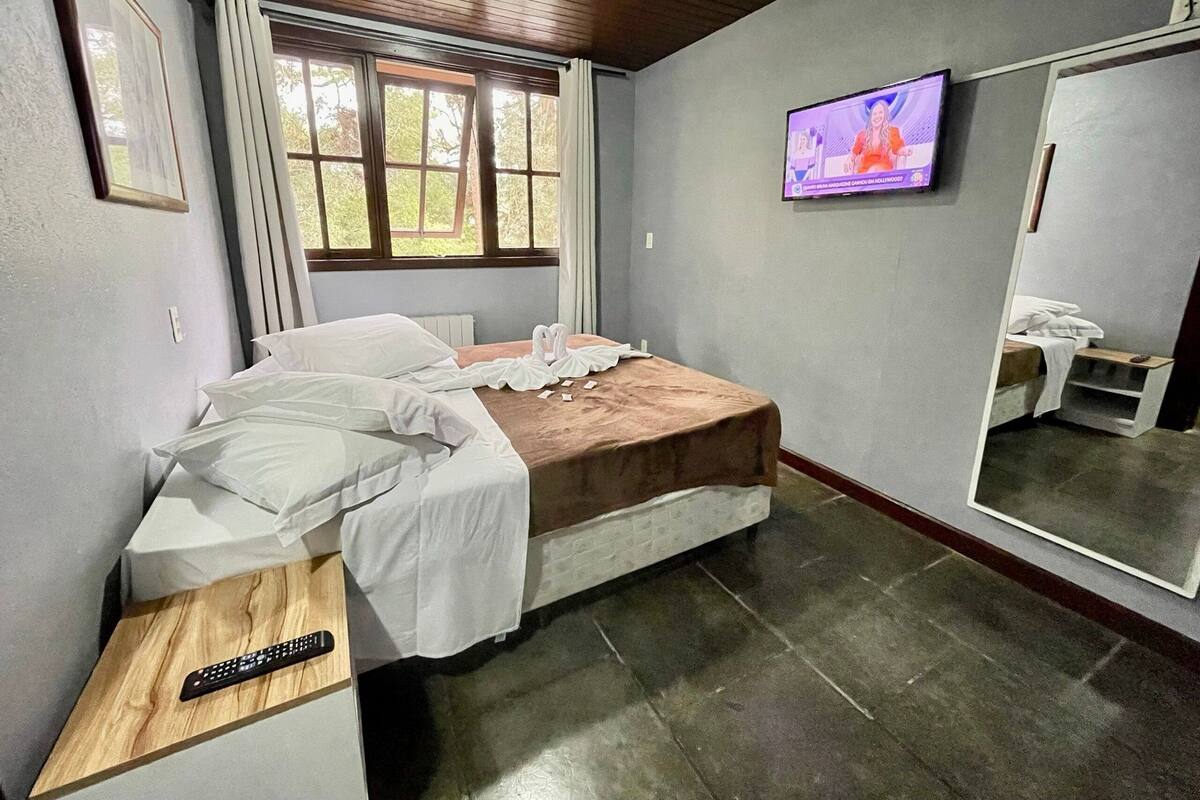 Un dormitorio con una cama, televisión, ventana y espejo.