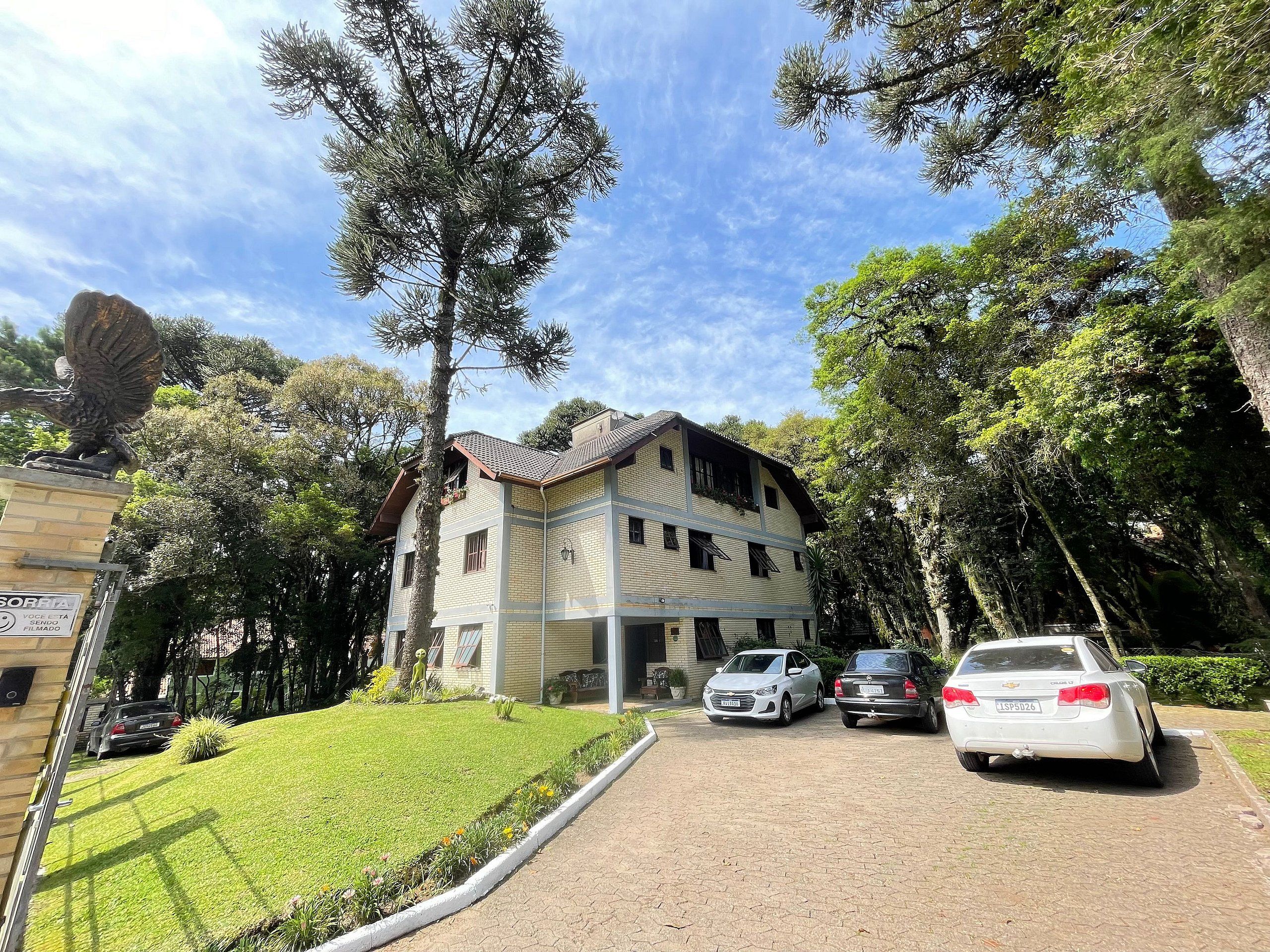 A two-story building with a tiled roof, surrounded by trees and parked cars.
