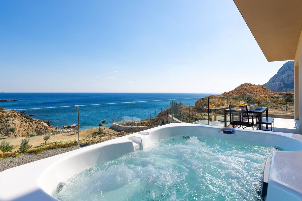 A hot tub with a view of the ocean and a table with chairs.