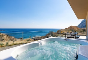 Un jacuzzi con vista al océano y una mesa con sillas.