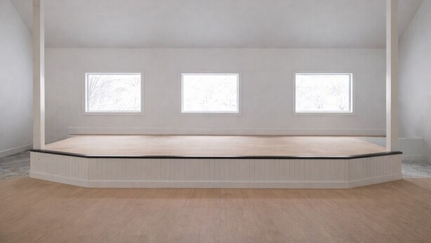 A room with a sloped ceiling, three windows, and a wooden floor.