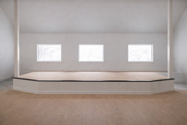 A room with a sloped ceiling, three windows, and a wooden floor.