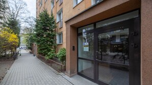 En byggnad med en entré som har en glasdörr, en asfalterad gångväg och en cykel som står parkerad vid sidan om.