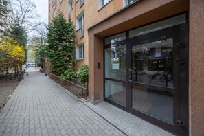 Ein Gebäude mit Glastür, einem gepflasterten Weg und einem Fahrrad am Rand.