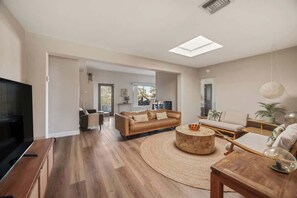 A spacious living room with a large TV, a round coffee table, and a sofa. - Zen Palm Desert Bungalow (Palm Desert)
