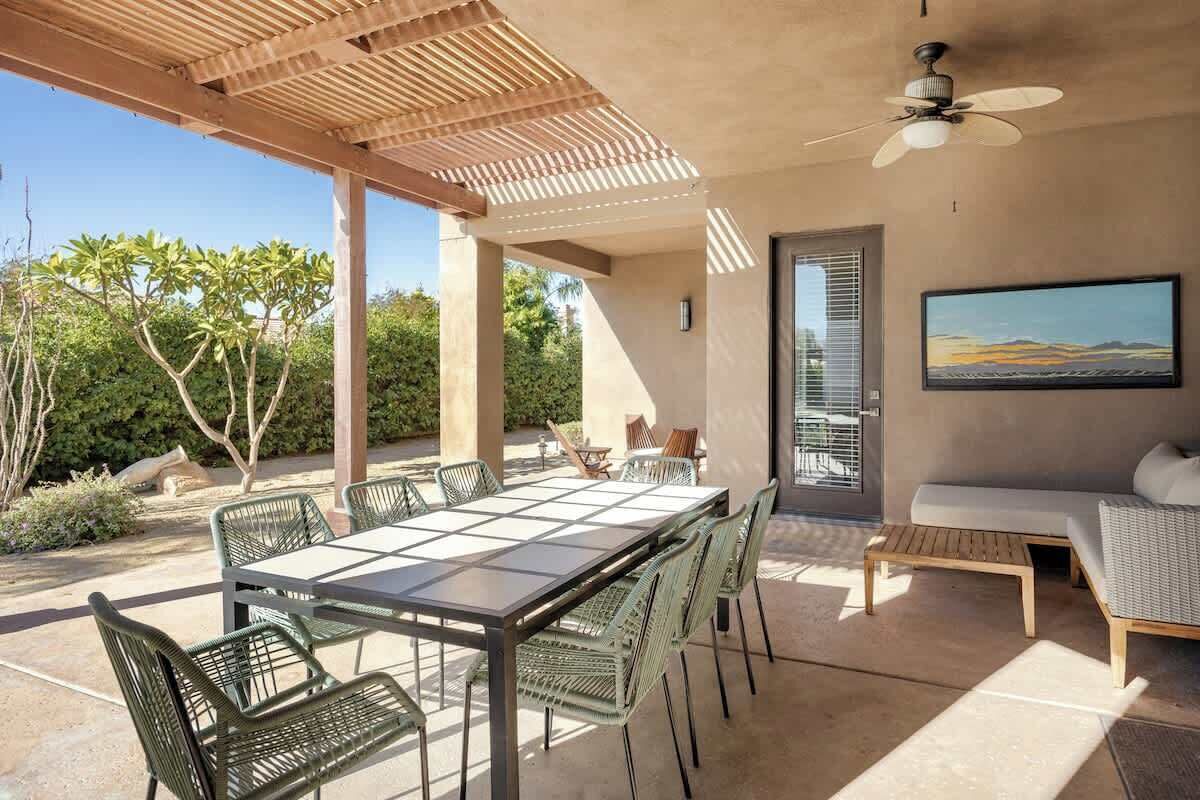 Une terrasse extérieure avec une table et des chaises, un ventilateur de plafond et un canapé.