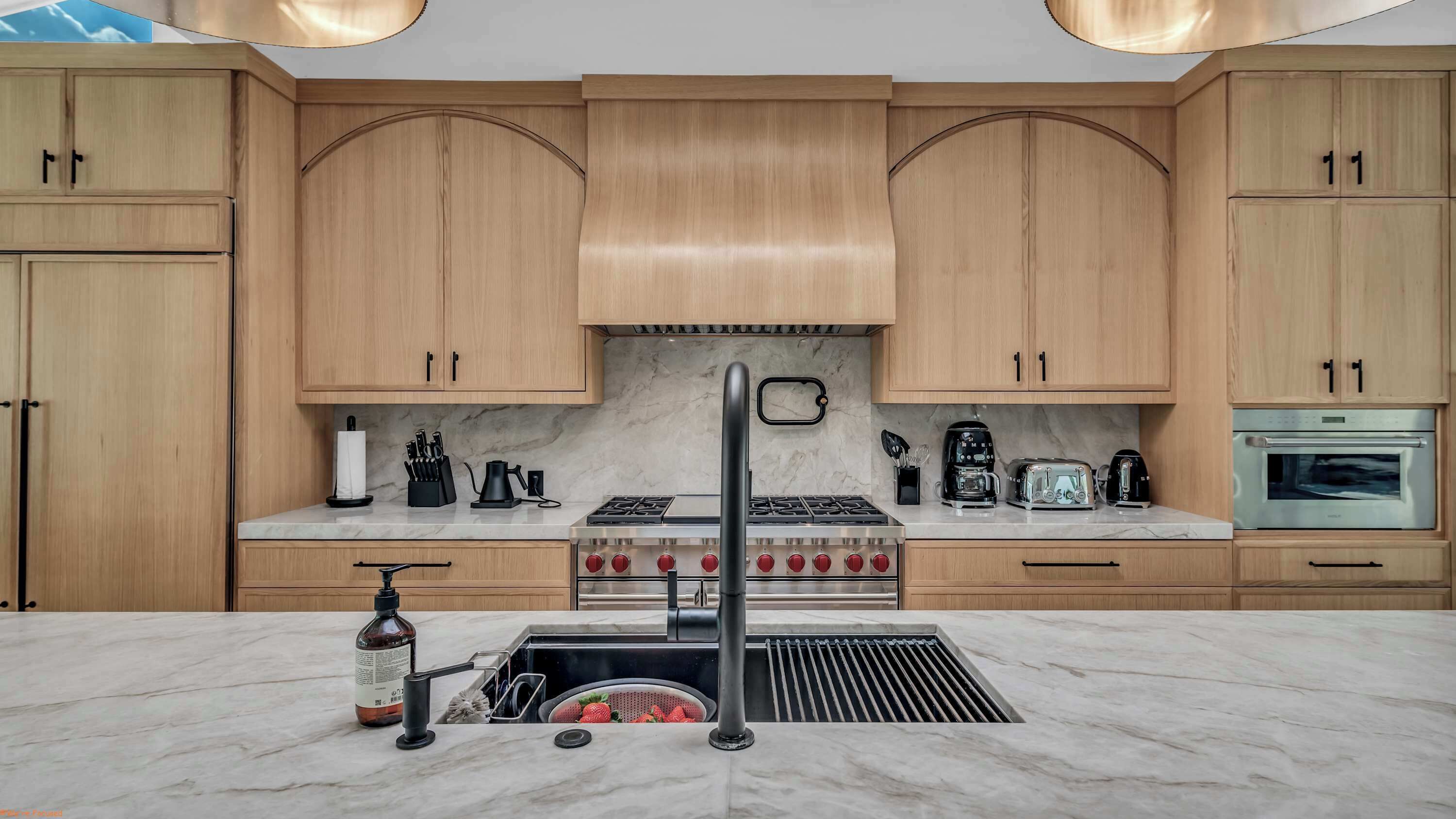 A modern kitchen with wooden cabinets, a stainless steel stove, and a built-in oven.