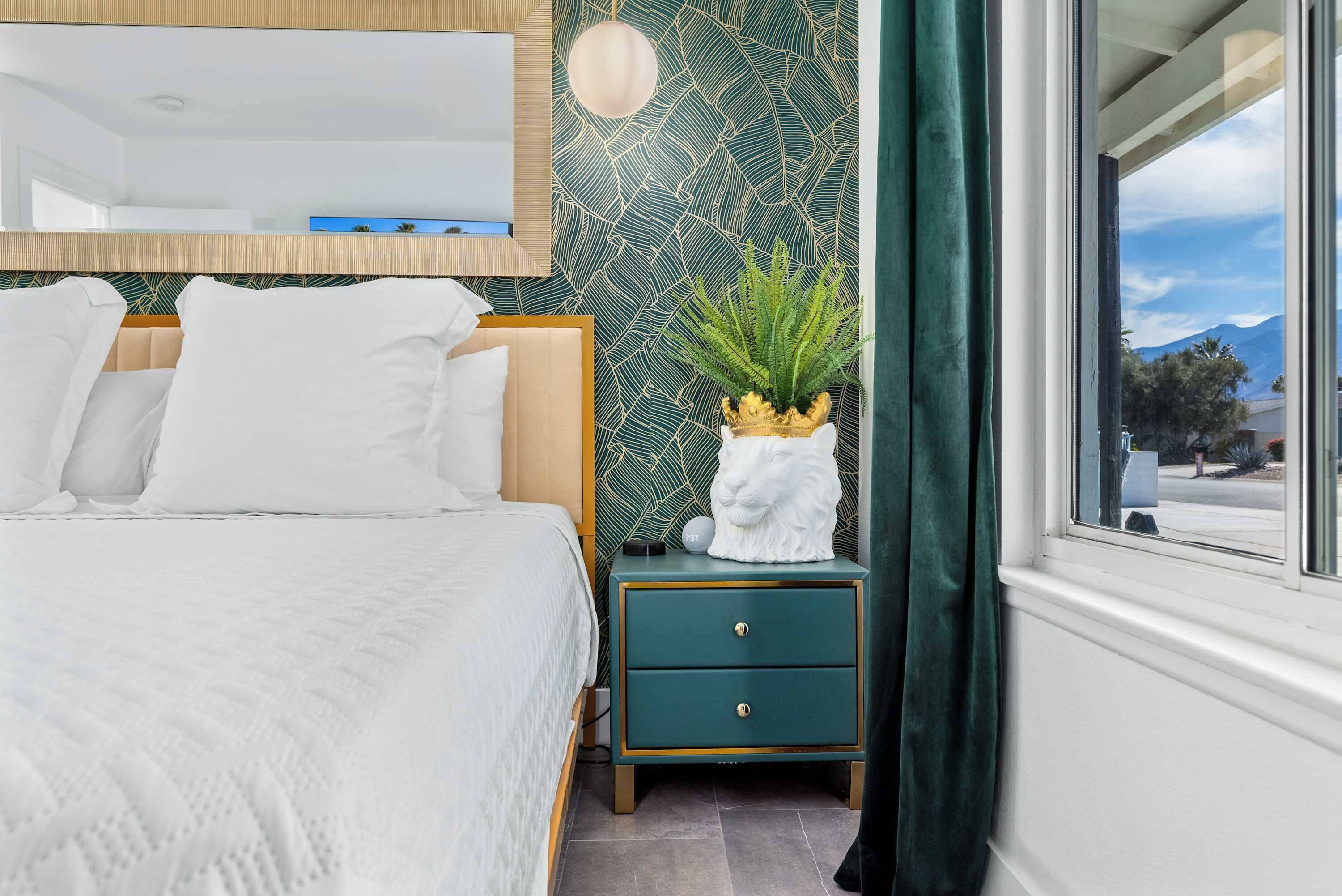 A neatly arranged bedroom with a bed, bedside table, and a view of the outdoors.