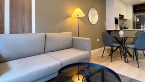 A modern living room with a sofa, a glass coffee table, and a dining area with chairs and a table. - w Modern Cozy 2BR in the Heart of San Isidro (Lima)