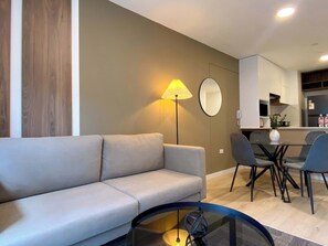A modern living room with a sofa, a glass coffee table, and a dining area with chairs and a table. - w Modern Cozy 2BR in the Heart of San Isidro (Lima)