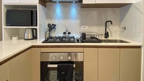 A compact kitchen with a gas stove, oven, microwave, and a coffee maker on the countertop. - w Modern Cozy 2BR in the Heart of San Isidro (Lima)