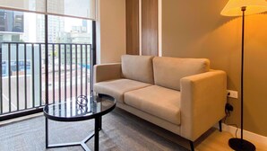 A modern living room with a sofa, a glass table, and a floor lamp. - w Modern Cozy 2BR in the Heart of San Isidro (Lima)