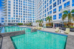 A hotel pool area with multiple lounge chairs and a large building in the background. - w Amazing Comfy 1BR w Pool on Avenida Balboa (Panama City)