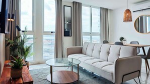 A modern living room with a sofa, a glass coffee table, and a dining area with a table and chairs. - w Amazing Comfy 1BR w Pool on Avenida Balboa (Panama City)