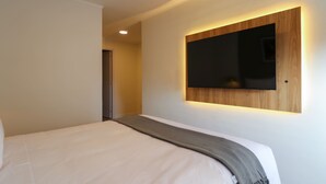 Ein modernes Hotelzimmer mit einem großen Bett, einem an der Wand befestigten Fernseher und einer Wandverkleidung aus Holz.