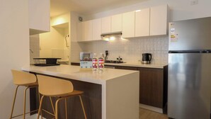 Eine moderne Küche mit einer zentralen Kochinsel, Barhocker, einem Edelstahl-Kühlschrank und einer Mikrowelle.