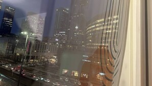 Bybillede med skyskrabere, en travl gade og et hotel med oplyst skiltning.