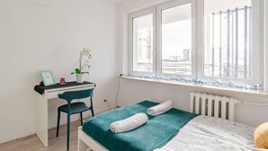 Et soveværelse med seng, skrivebord, stol, et vindue med udsigt og en radiator.