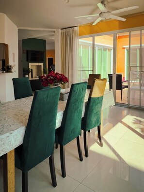 Comedor con mesa, sillas, ventilador de techo y vista a través de un ventanal.