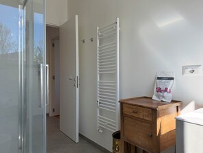 Ein Zimmer mit einer Schiebetür aus Glas, einem weißen Heizkörper, einem Holzschrank und einem Willkommen-Set an der Wand.