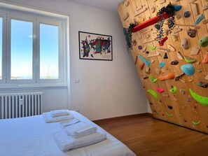 Ein Zimmer mit einem Bett, einer Kletterwand, einem Fenster und einer Heizung.