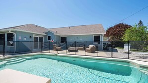 A pool area with a clear blue pool, a covered seating area with chairs, and a building with a grey roof. - Spacious 5BR Pool Oasis Near Disney Resort (Sebastian)