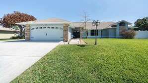 A residential house with a garage, a well-maintained lawn, and a clear sky. - Spacious 5BR Pool Oasis Near Disney Resort (Sebastian)