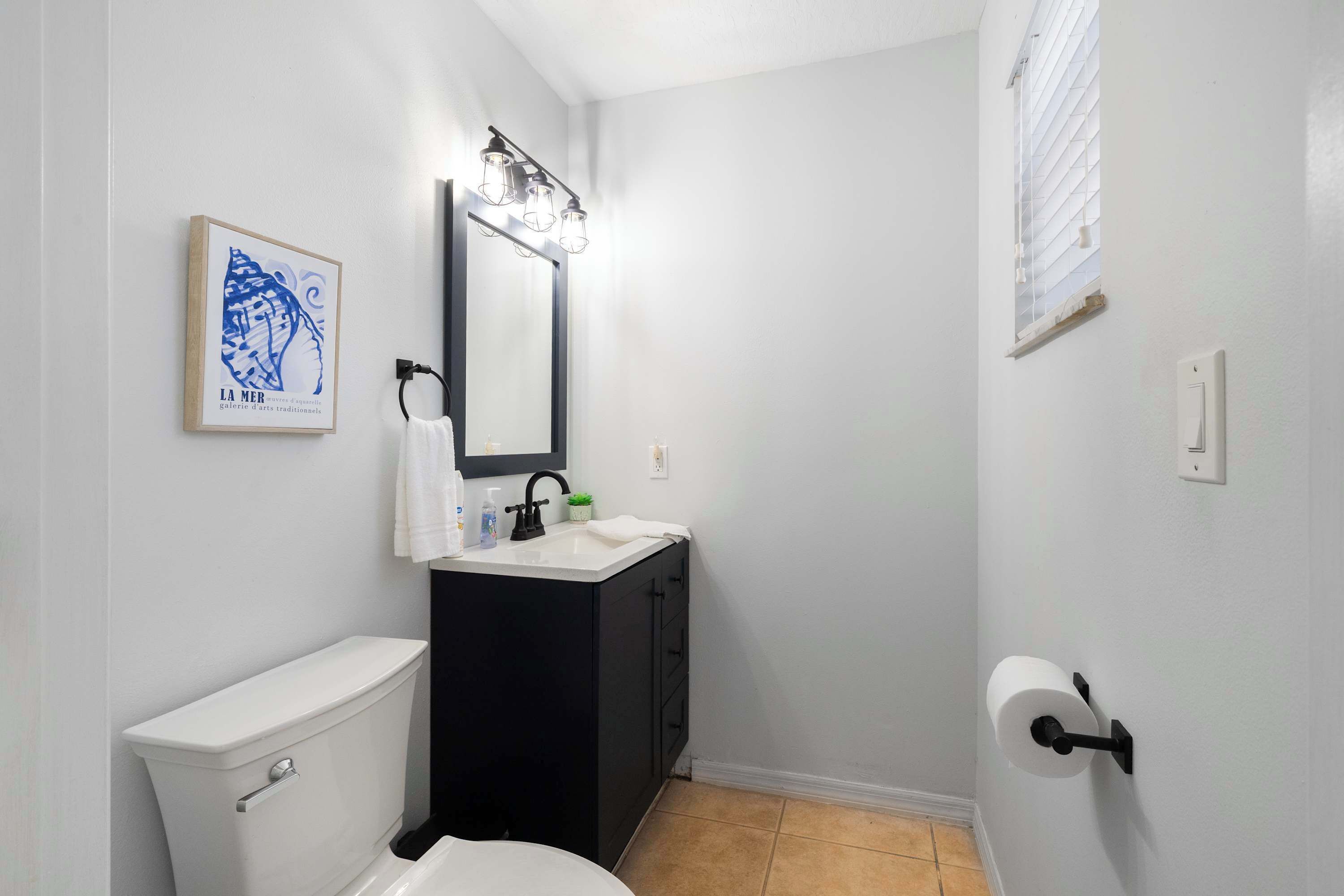 Une salle de bain équipée de toilettes, d’un lavabo, d’un miroir et d’un porte-serviettes.
