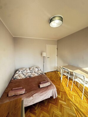 A room with a bed, a desk, a chair, a lamp, and a door. - Golden Escape 3 Rooms Apart (Warsaw)