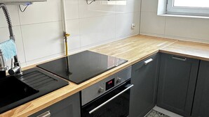 Una cocina con estufa negra, un fregadero y una ventana.