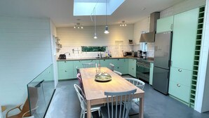 Una cocina moderna con tragaluces, una mesa de comedor con sillas y electrodomésticos integrados.