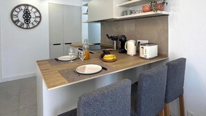 Una cucina moderna con un piano di lavoro in legno, una sveglia e un'area pranzo con sedie grigie.