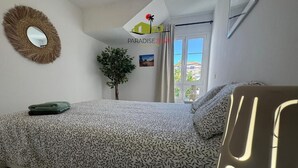 Una camera da letto con un letto, uno specchio, una pianta e una finestra.
