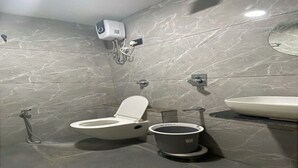 A modern bathroom with a toilet, bidet, and sink. - HOTEL HILLS (Ahmedabad)
