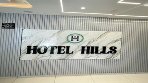 A marble wall with a sign for 'HOTEL HILLS' and a check-in time sign. - HOTEL HILLS (Ahmedabad)