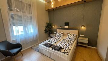 Une chambre à coucher avec un lit, une chaise, une plante et une fenêtre avec des stores.