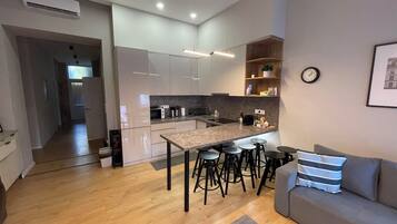 Une cuisine moderne avec un îlot central, des tabourets de bar, un canapé et une horloge au mur.