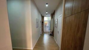 Un passadís amb terra de fusta, parets blanques i portes que donen a diferents habitacions.