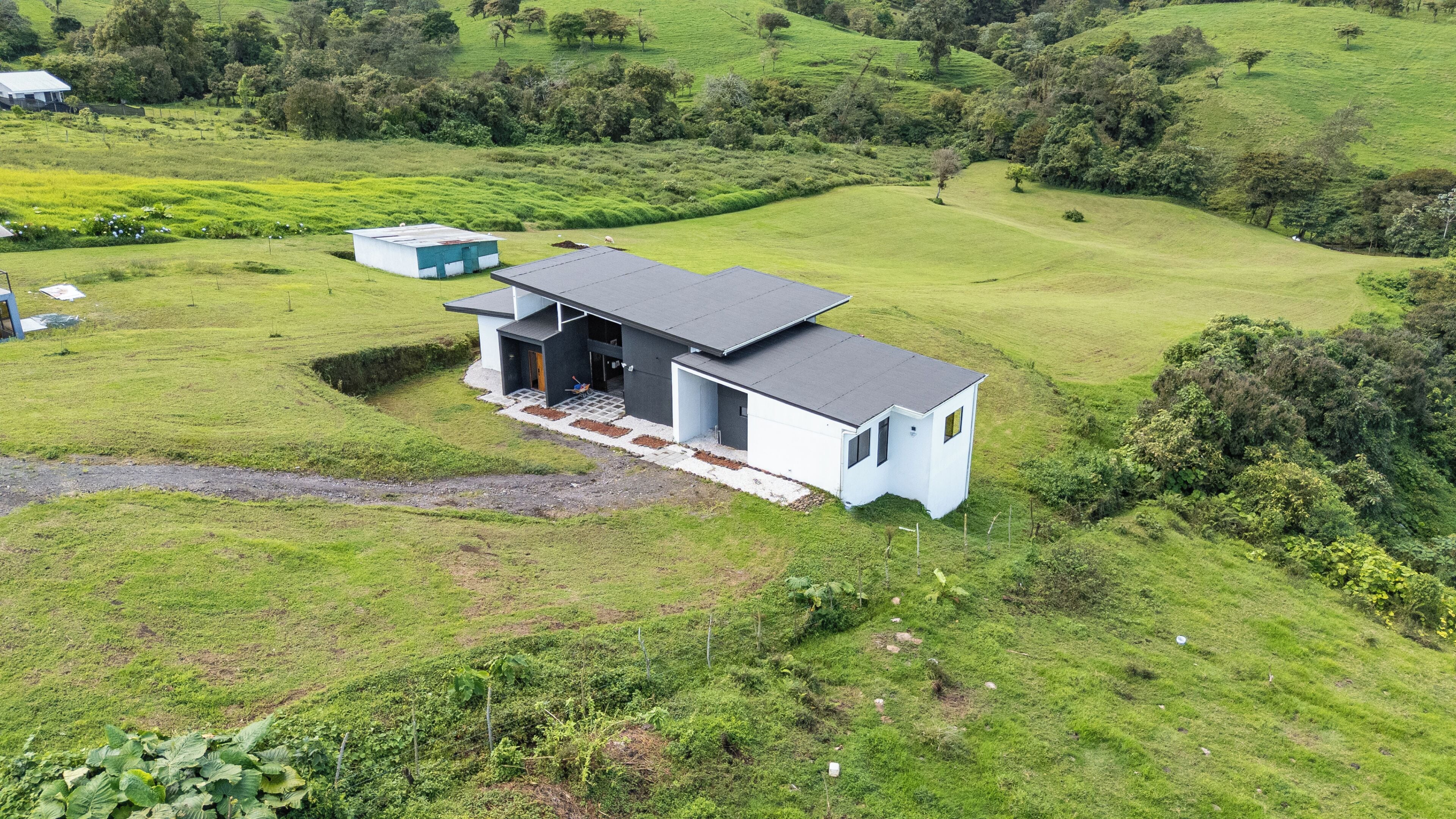 A modern house with a flat roof, a small porch, and a large open space.