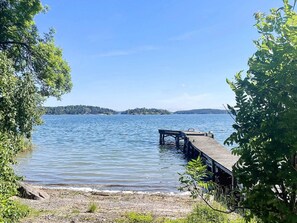A calm lake with a wooden dock extending into the water, surrounded by trees. - 4 Person Holiday Home in Akersberga (Akersberga)