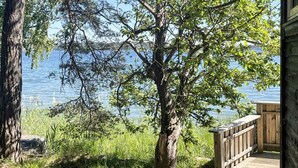 A wooden deck with a view of a lake and trees. - 4 Person Holiday Home in Akersberga (Akersberga)
