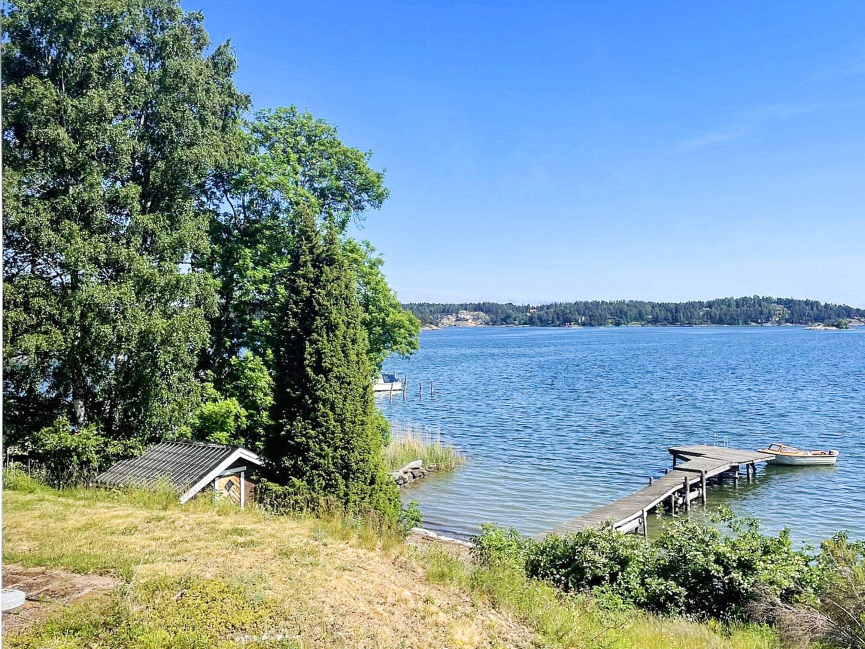 A lakeside property with a dock, a small building, and dense trees.